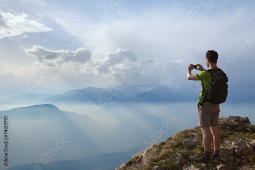 hiker taking photo of beautiful mountain landscape with mobile phone