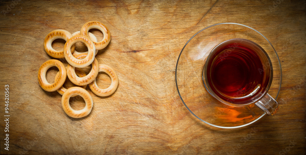 Fototapeta premium Cup of tea, bagels dry on the old rustic table wood background.