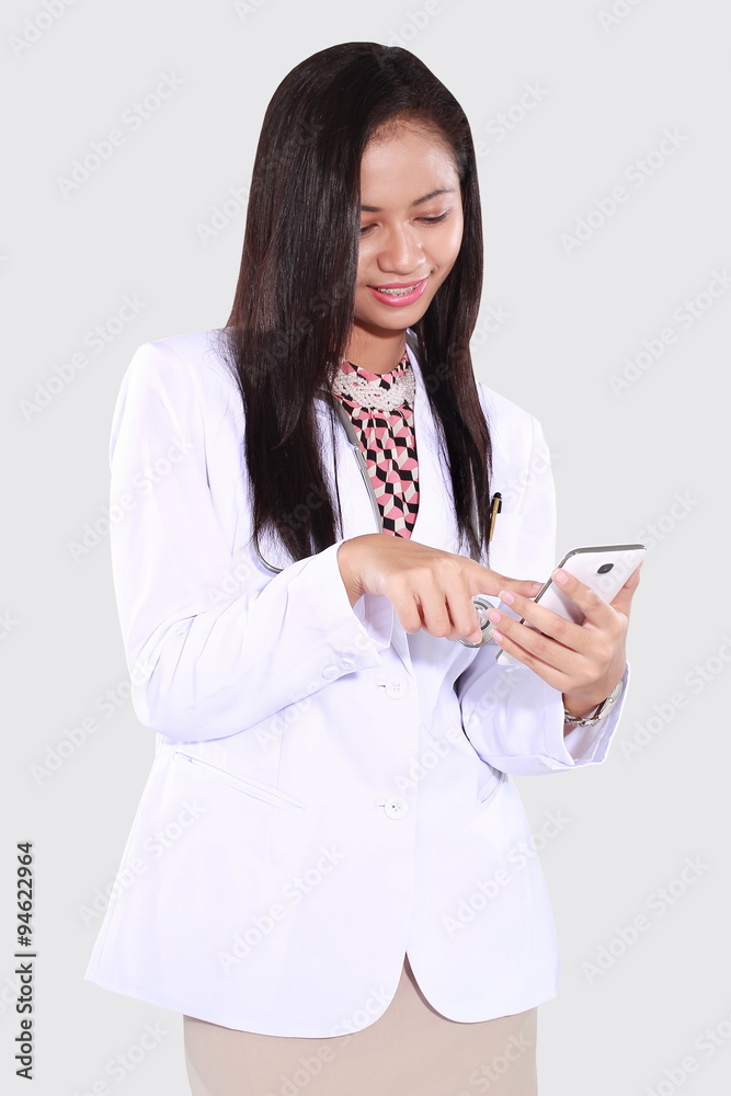 female doctor who was writing a message with a mobile phone, isolated on grey background female doctor who was writing a message with a mobile phone, isolated on grey background