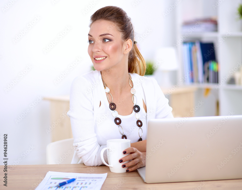 Cute businesswoman holding newspaper sitting at her desk in office