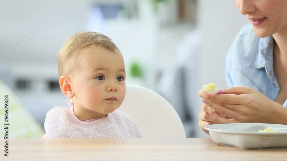 Baby girl eating lunch with help of her mommy Baby girl eating lunch with help of her mommy