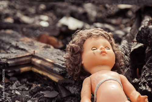 Abandoned child's baby doll with blue eyes on parched desert dirt.