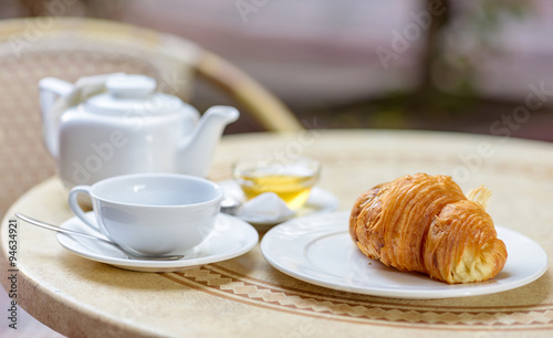 French croissant on white plate on a restaurant table