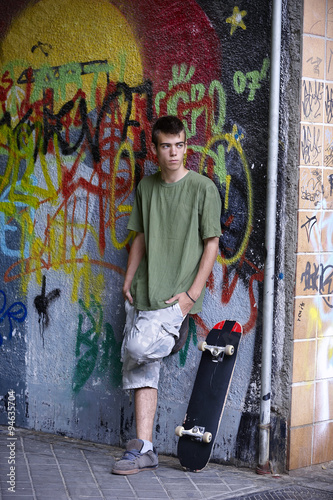 Young skater leaning against a wall with graffiti
