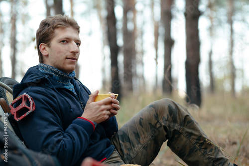 Fotografi Man tourist with bicycle sitting and snacking in forest