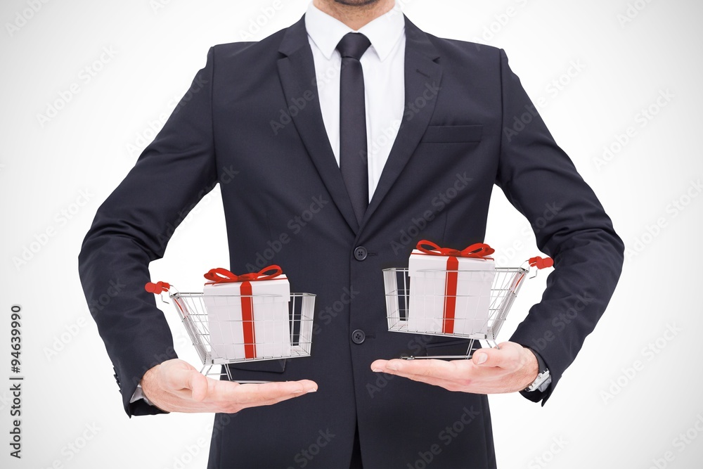 Composite image of businessman holding carts with gifts Composite image of businessman holding carts with gifts