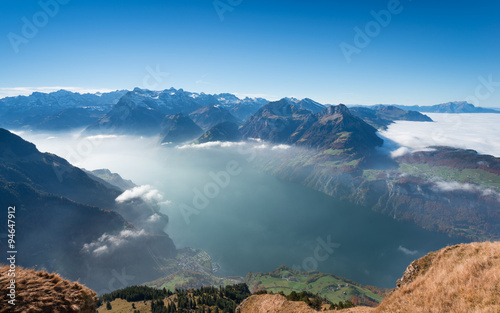 Aerial view of the top of mountains down to the lake in fog and clouds.
