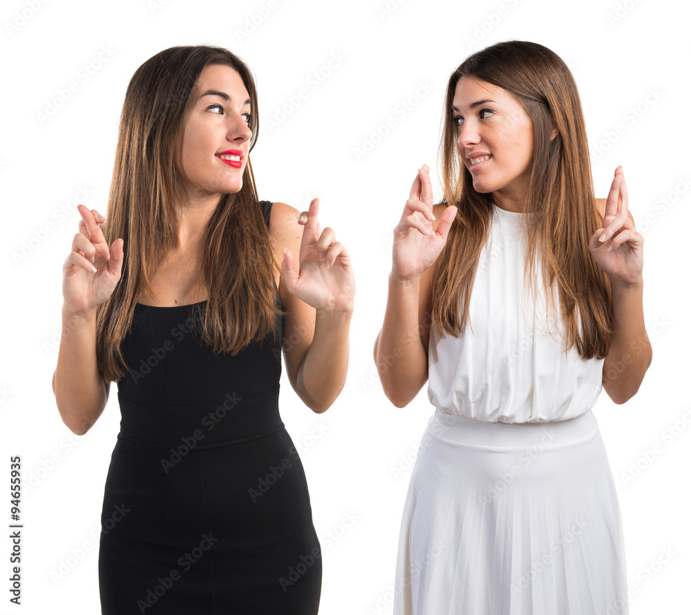 Twin sisters with their fingers crossing Twin sisters with their fingers crossing