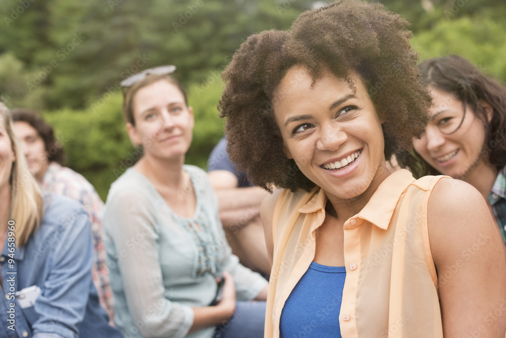 A woman in a group outdoors, laughing. A woman in a group outdoors, laughing.