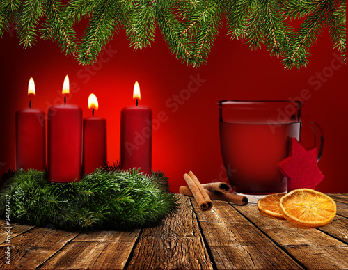 Glühwein und Adventskranz vor Rotem Hintergrund