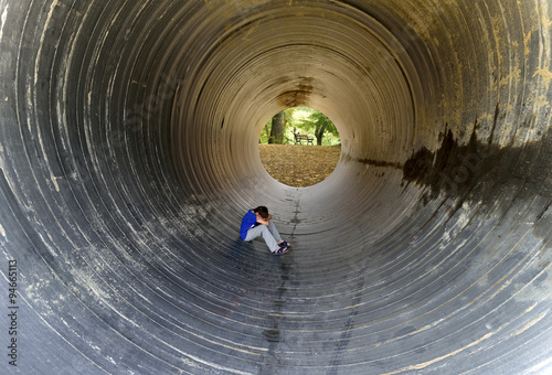 child sitting in the tunnel and rear benches under trees photo