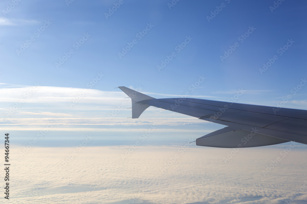 Fototapeta premium An airplane wing against the sky and clouds up in the air. Image has a vintage effect applied.