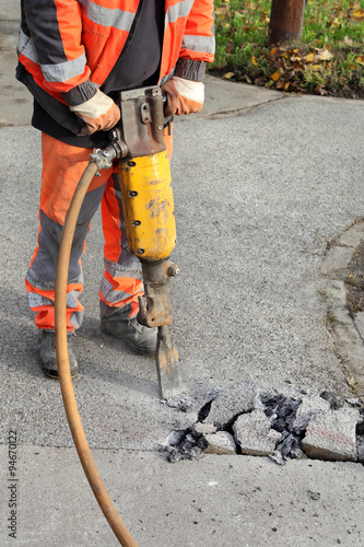 Bilde på lerret Worker at construction site demolishing asphalt with pneumatic plugger hammer