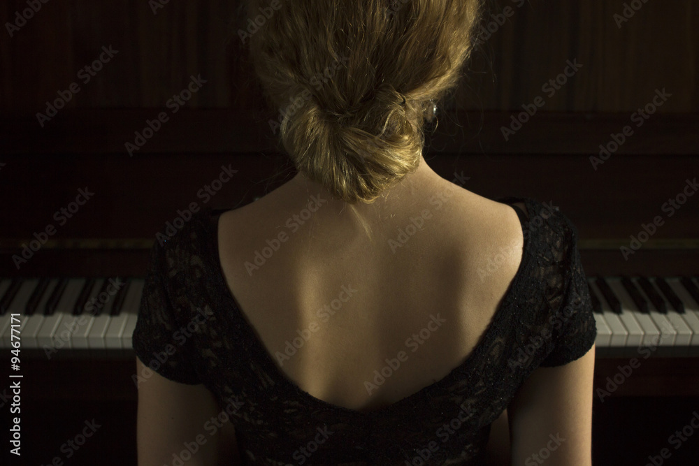 Fototapeta premium Young beautiful girl playing on the piano