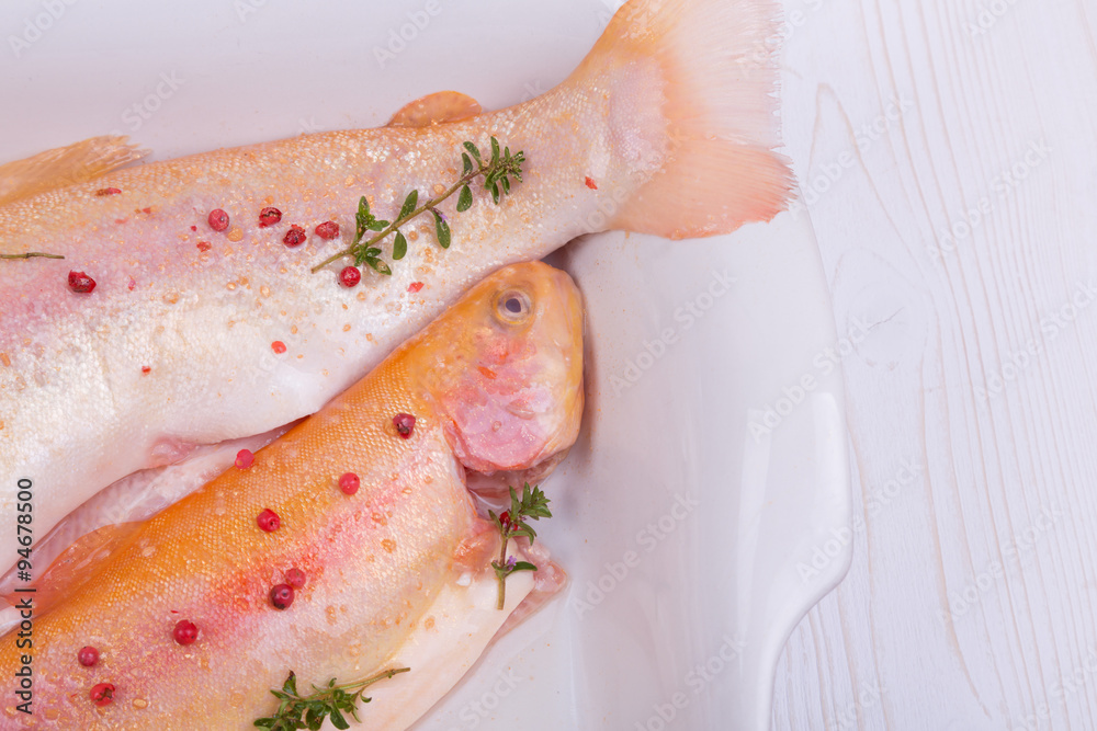 Fototapeta premium golden trout on a baking dish with red pepper and thyme. gold fish. home kitchen.