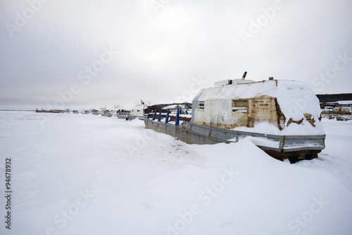 Abandoned fishing boats in the frozen river. © amarinchenko106