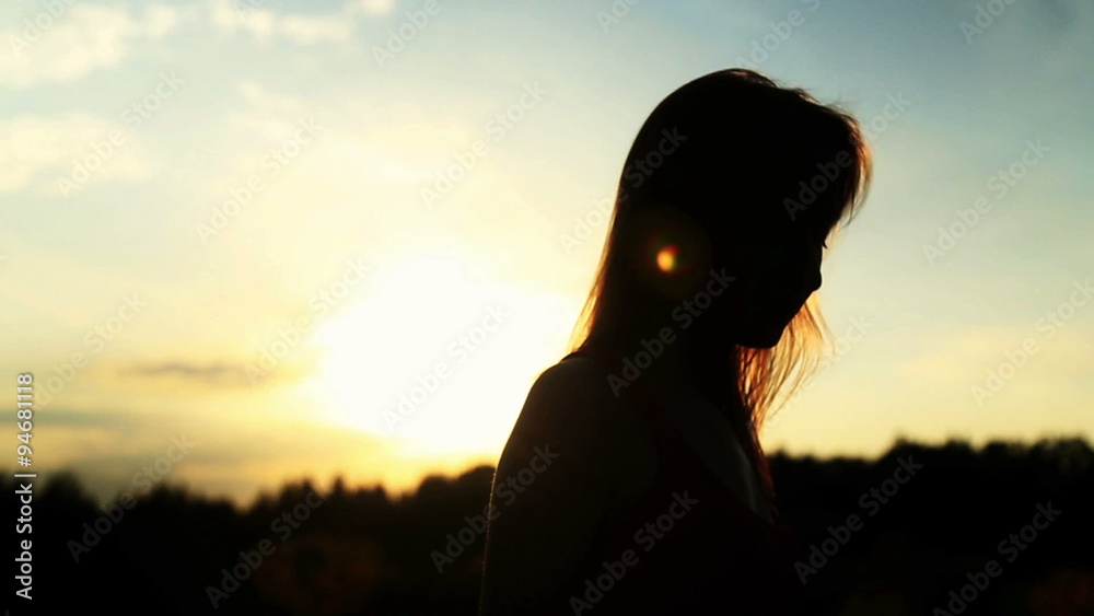A silhouette of a woman on a sunset turns her head and dancing A silhouette of a woman on a sunset turns her head and dancing