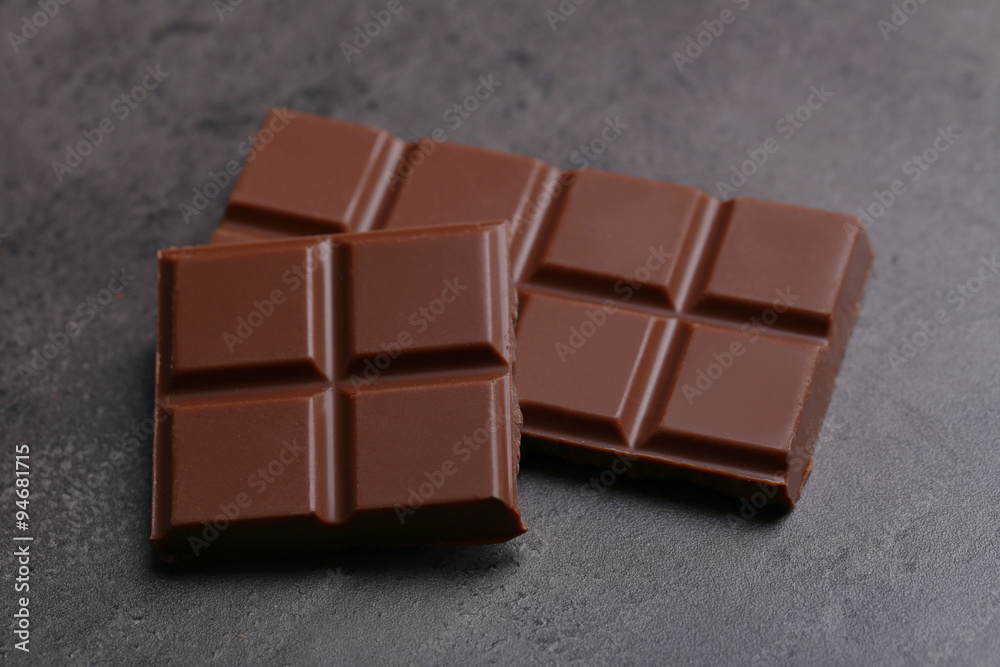 Milk chocolate pieces on gray background Milk chocolate pieces on gray background