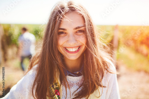 Smiling teenage girl outdoors on sunny day. Closeup of cute brunette young woman wearing casual clothes.