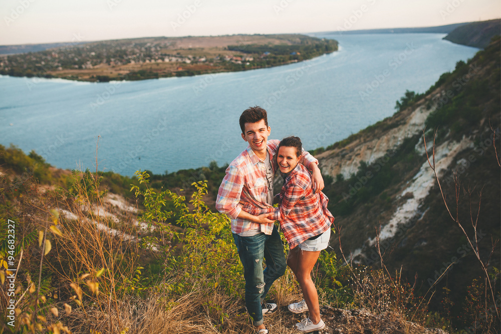 Naklejka premium Young couple in love outdoor. Portrait of a happy couple hugging on nature with river background.