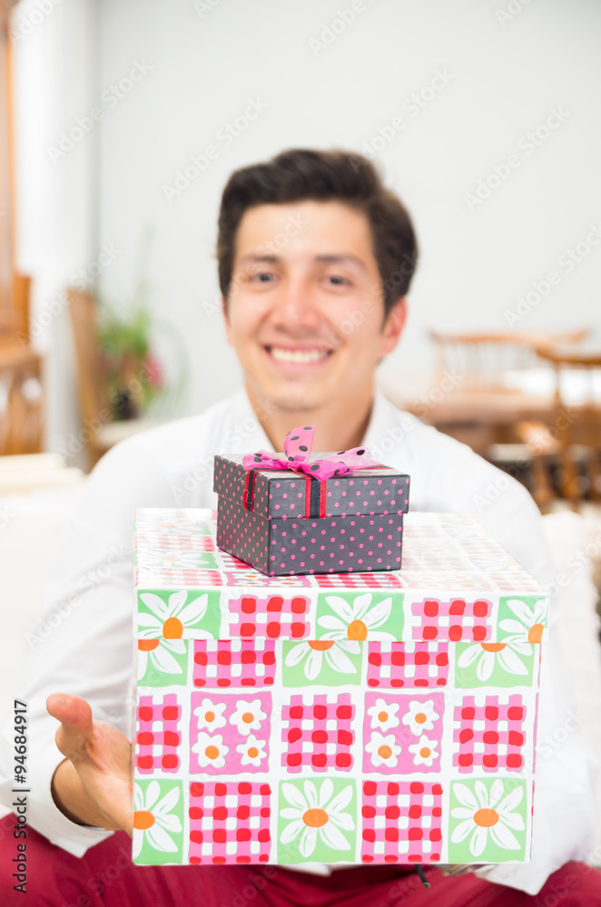 Handsome joyful young man holding Christmas present box Handsome joyful young man holding Christmas present box