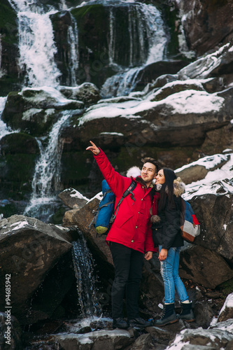 Beautiful smiling hipster couple standing on a rock, mountains,