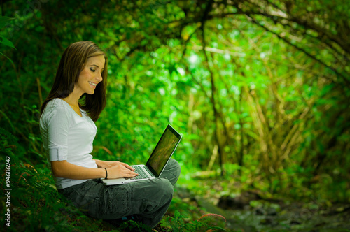 Beautiful young girl using laptop outdoors in the wild enjoying excellent connectivity