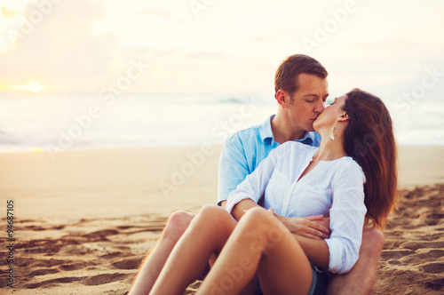 Couple Relaxing on the Beach Kissing and Watching the Sunset