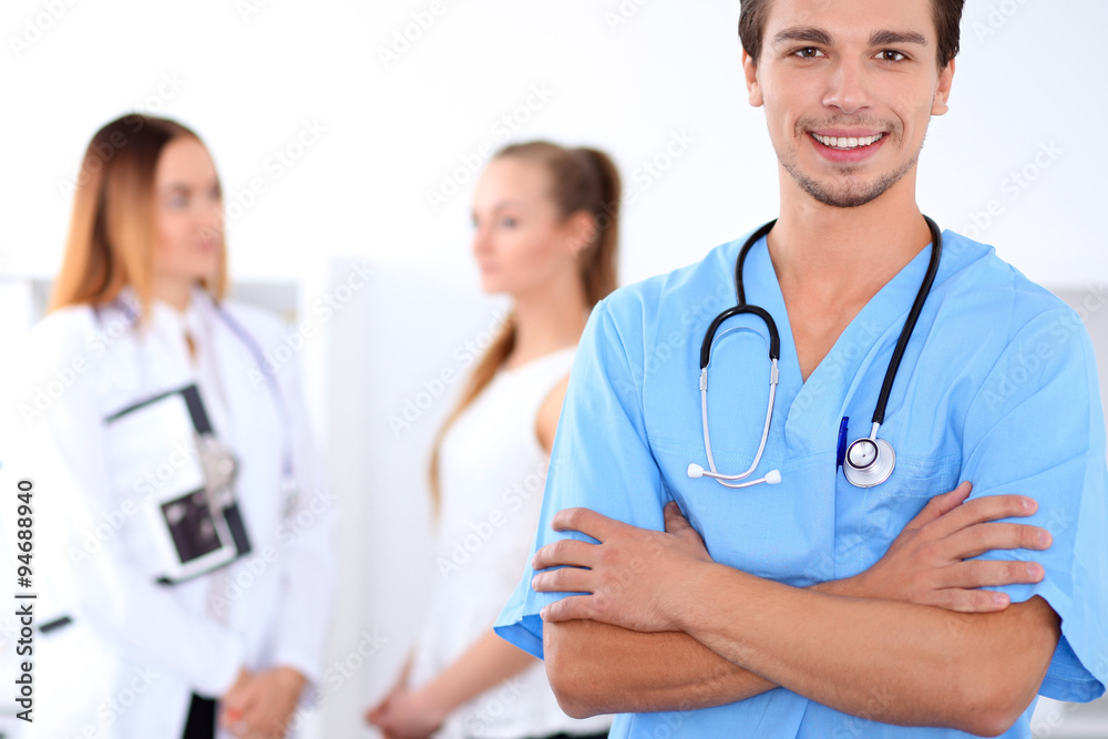 Attractive male doctor in front of medical group, crossed arms Attractive male doctor in front of medical group, crossed arms