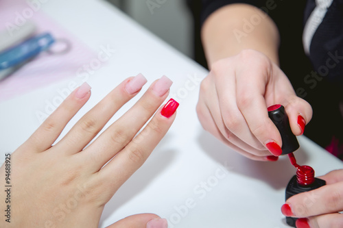Paint lacquer red nails in beauty salon
