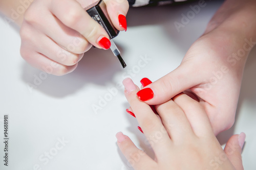 Paint lacquer red nails in beauty salon