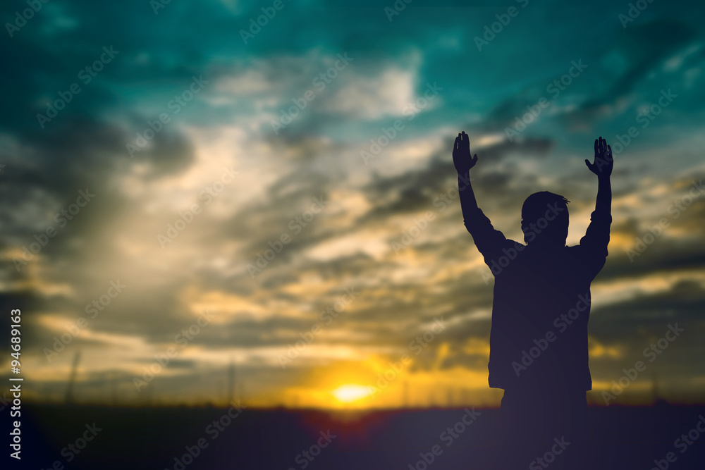 Silhouette of man with raised hands over blur cross concept for