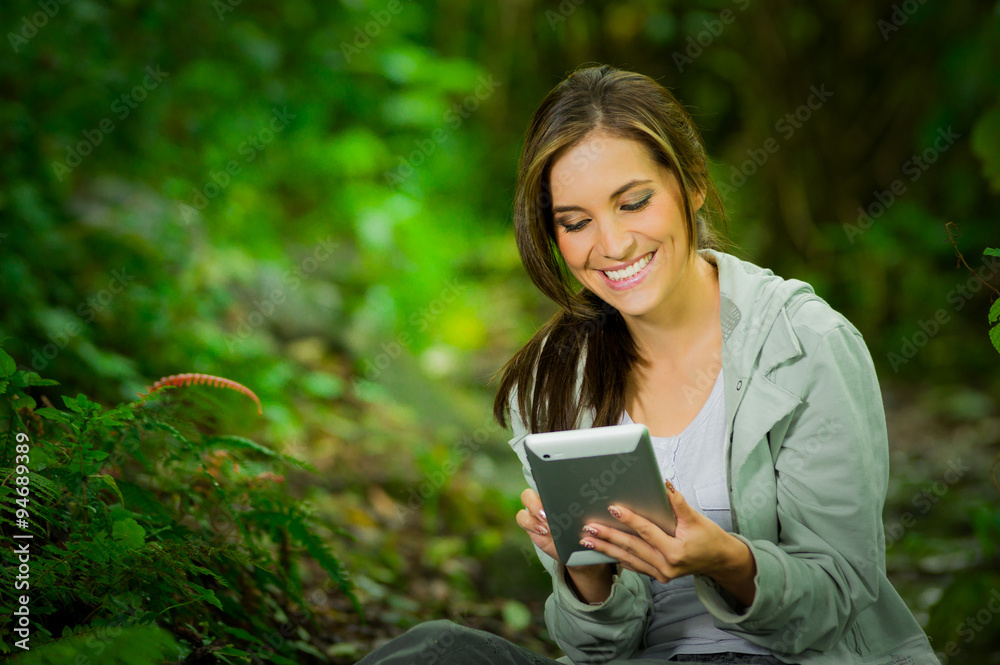 Beautiful young girl holding a tablet enjoying excellent connectivity in the jungle Beautiful young girl holding a tablet enjoying excellent connectivity in the jungle
