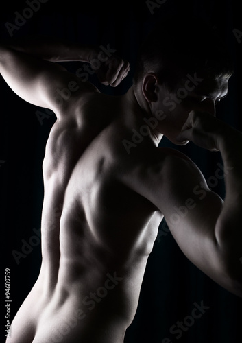strong man's body seen from behind isolated in dark © tavrox