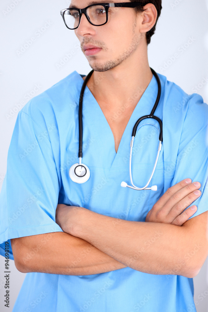 Attractive male doctor standing near the wall, crossed arms Attractive male doctor standing near the wall, crossed arms