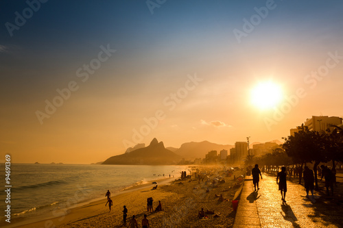 Unidentifiable silhouettes enjoy late afternoon sun rays on Ipanema beach in Rio de Janeiro, Brazil.  Ipanema is one of the most expensive places to live in Rio, photo