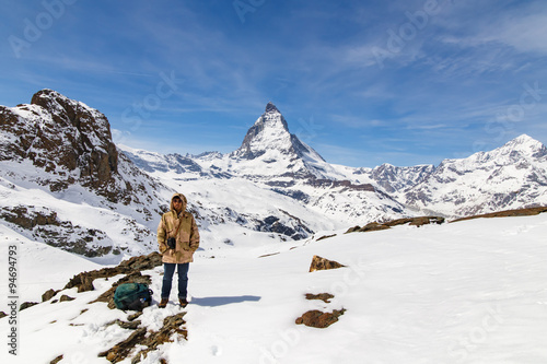 A man standing on the snow with the background of Matterhorn.