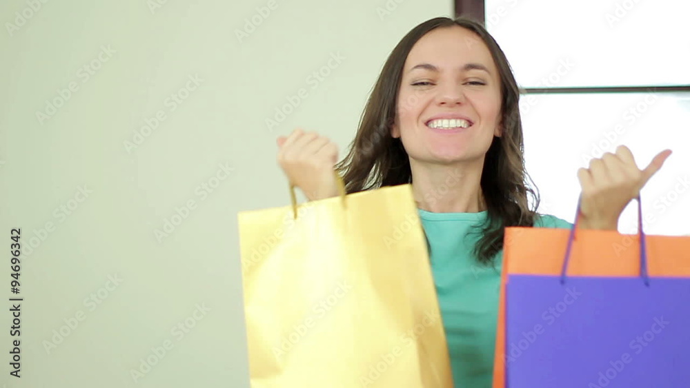 Happy jumping girl with shopping bags showing thumbs up, slow motion Happy jumping girl with shopping bags showing thumbs up, slow motion