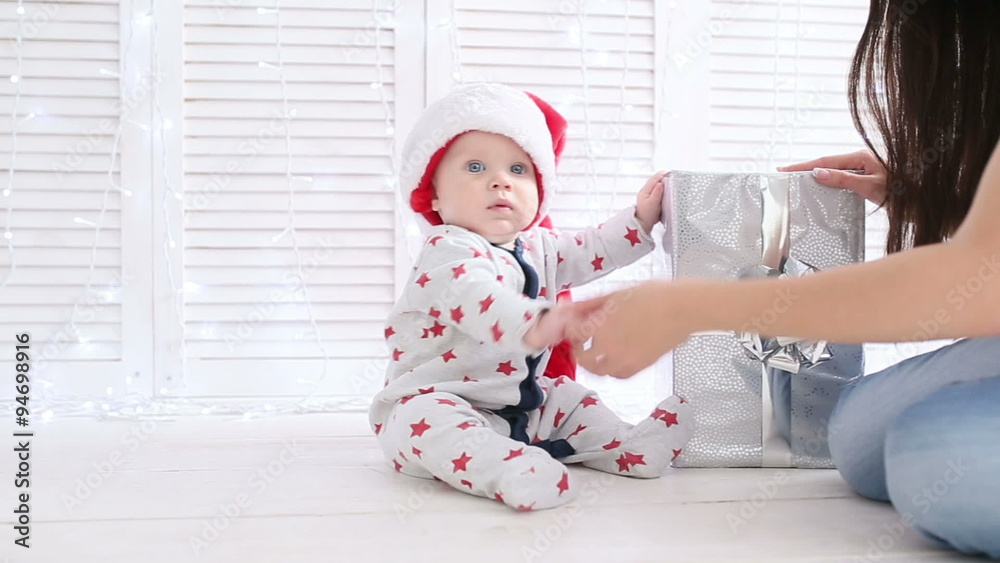 Beautiful little baby celebrates Christmas. New Year's holidays. Baby in a Christmas costume with gift Beautiful little baby celebrates Christmas. New Year's holidays. Baby in a Christmas costume with gift