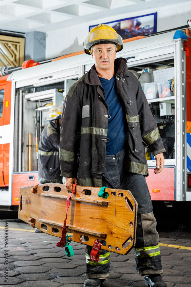 Fototapeta premium Confident Firefighter Carrying Wooden Stretcher