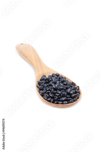 Black beans with wooden spoon isolated on white.