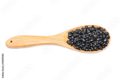 Black beans with wooden spoon isolated on white.