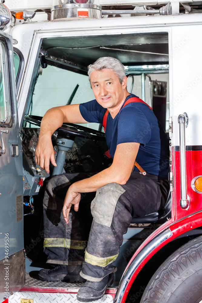 Obraz premium Smiling Male Firefighter Sitting In Truck