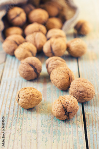Pile of walnuts in shell inbag on a wooden background