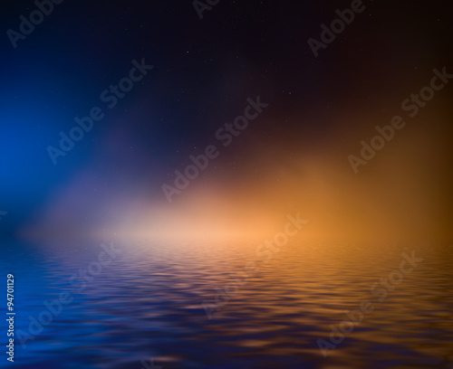 Night sky with colorful cloud and stars reflected in water.