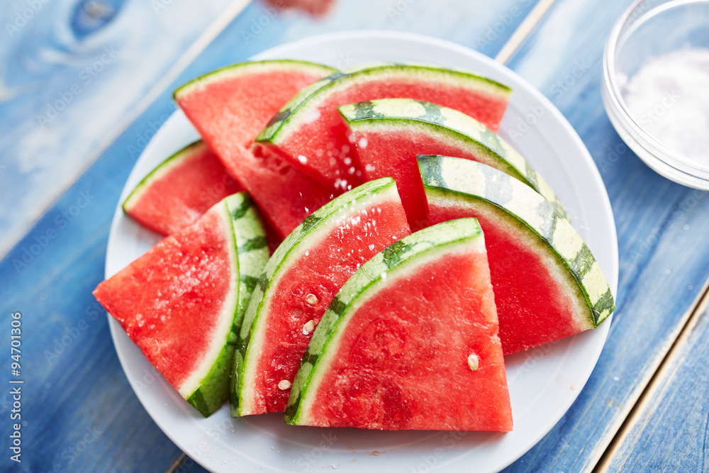 sprinkling salt on a pile of watermelon slices sprinkling salt on a pile of watermelon slices