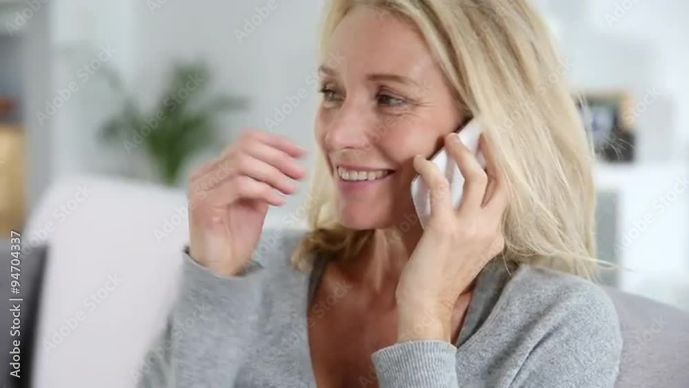 Mature woman, using a mobil phone at home