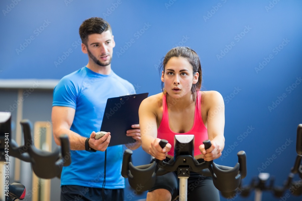 Woman on exercise bike with trainer timing her