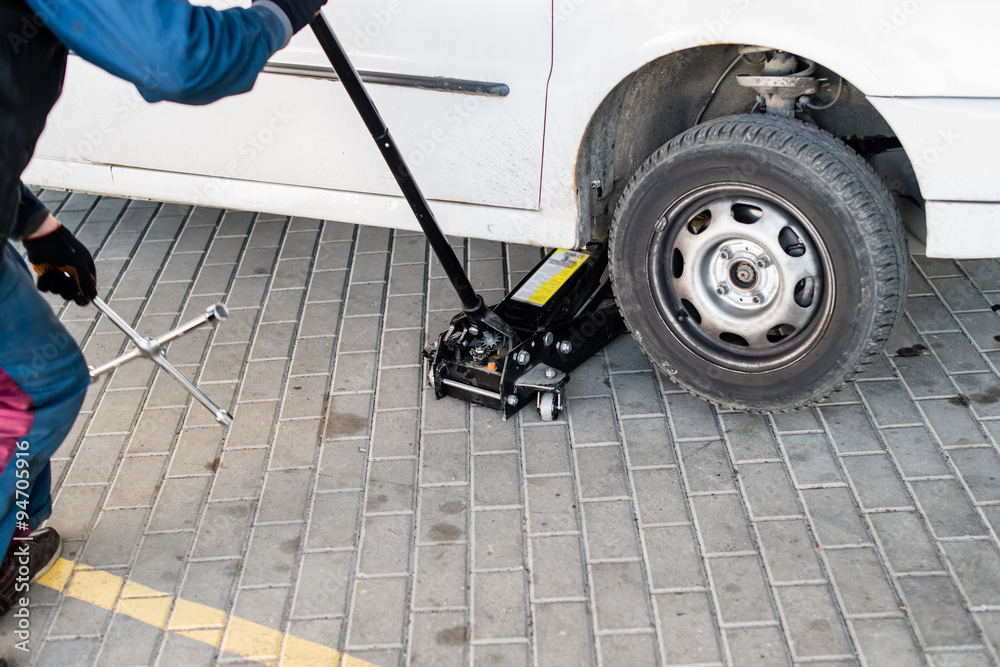 Fototapeta premium mechanic changing a wheel of a modern car (shallow DOF; color to