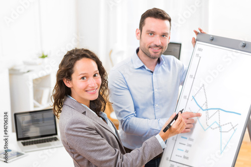 Slika na platnu Business man and woman, analysing stats on a paperboard